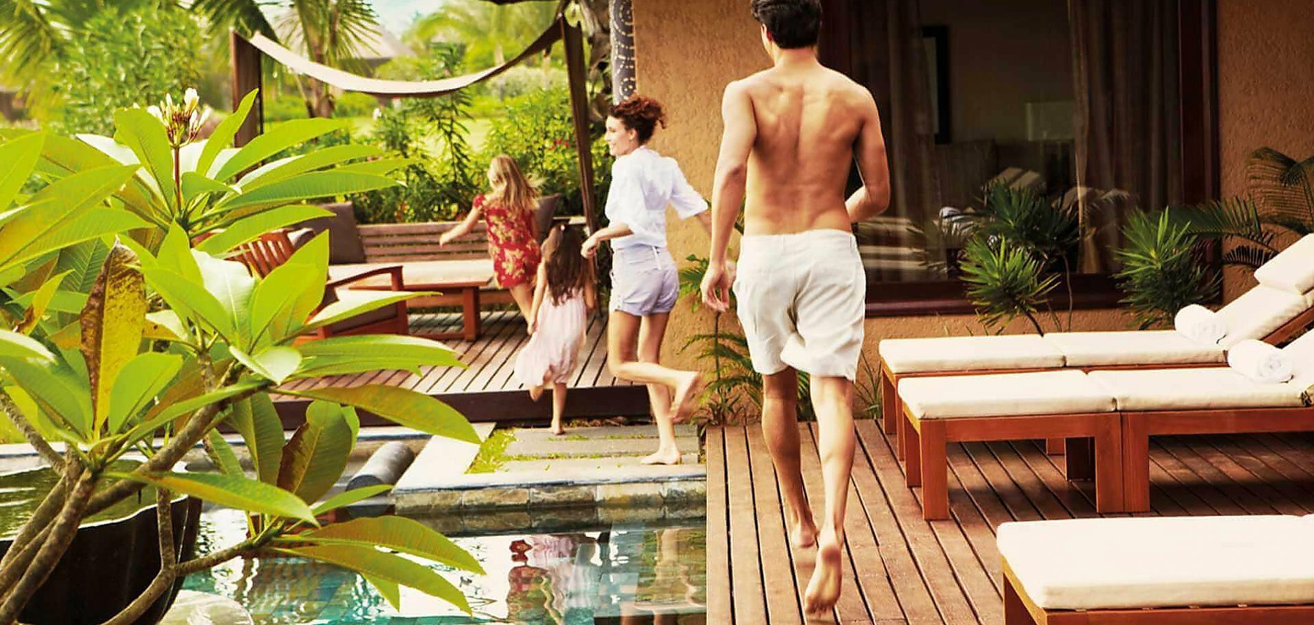 Børn løber forrest efterfulgt af mor og far ved poolen af deres privat villa på resortet Shanti Maurice